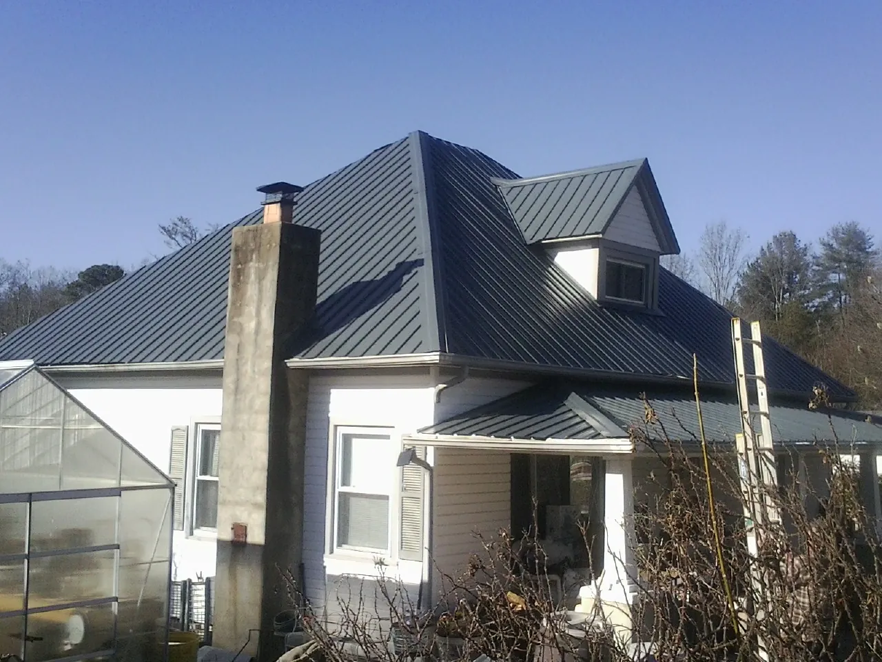 Dark blue standing seam metal roof on a white farmhouse with dormer — Slate & Tile Roof Repair by Roofing Brothers in Benton City