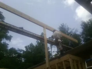 Carpenter setting a ridge beam over a new addition frame — Ice Dam Removal by Roofing Brothers in Benton City