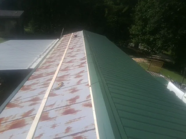 Old rusted panels beside newly installed green metal roofing — Wind Damage Roof Repair by Roofing Brothers in Benton City