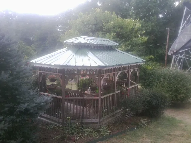Green metal roof on a backyard gazebo surrounded by garden beds in Benton City