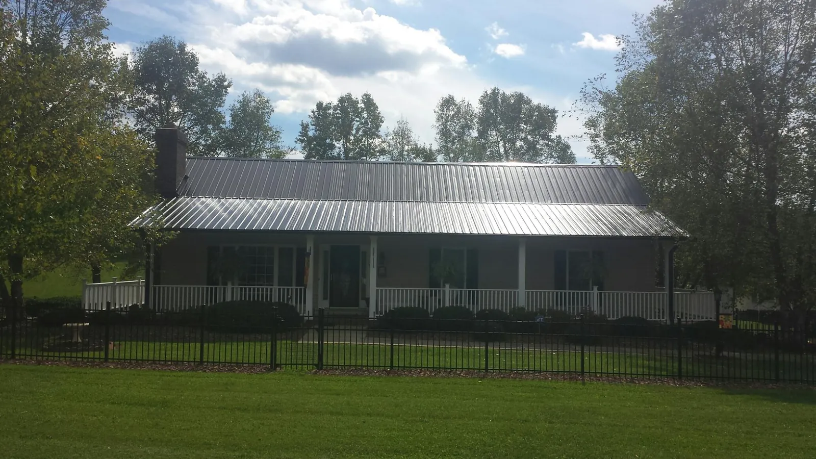 Gray metal roof on a brick ranch with a full width front porch — Gutter Guard Installation work by our crew in Benton City