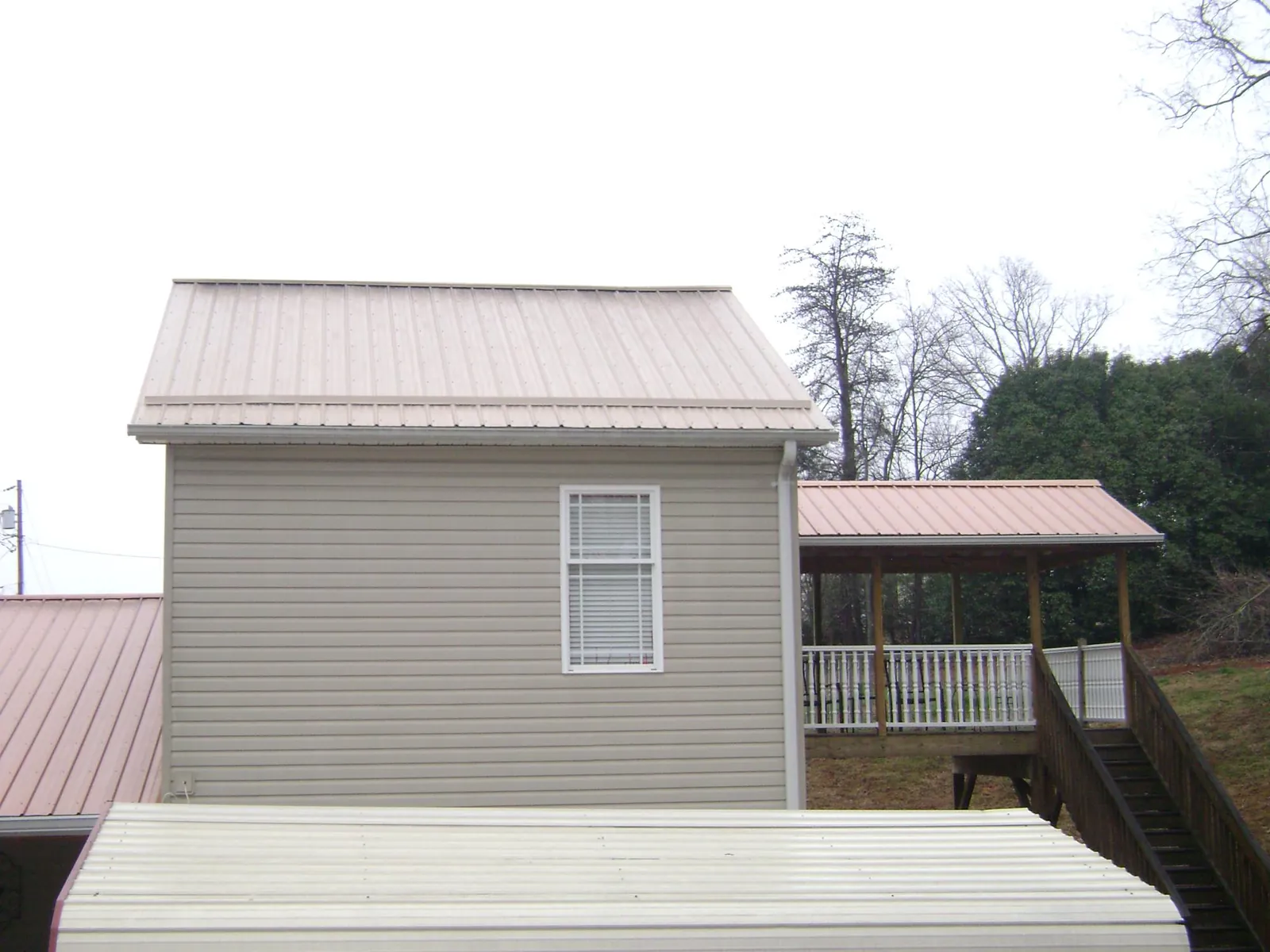 Tan metal roofs on a two story addition and attached porch, from a Roof Replacement job in Benton City
