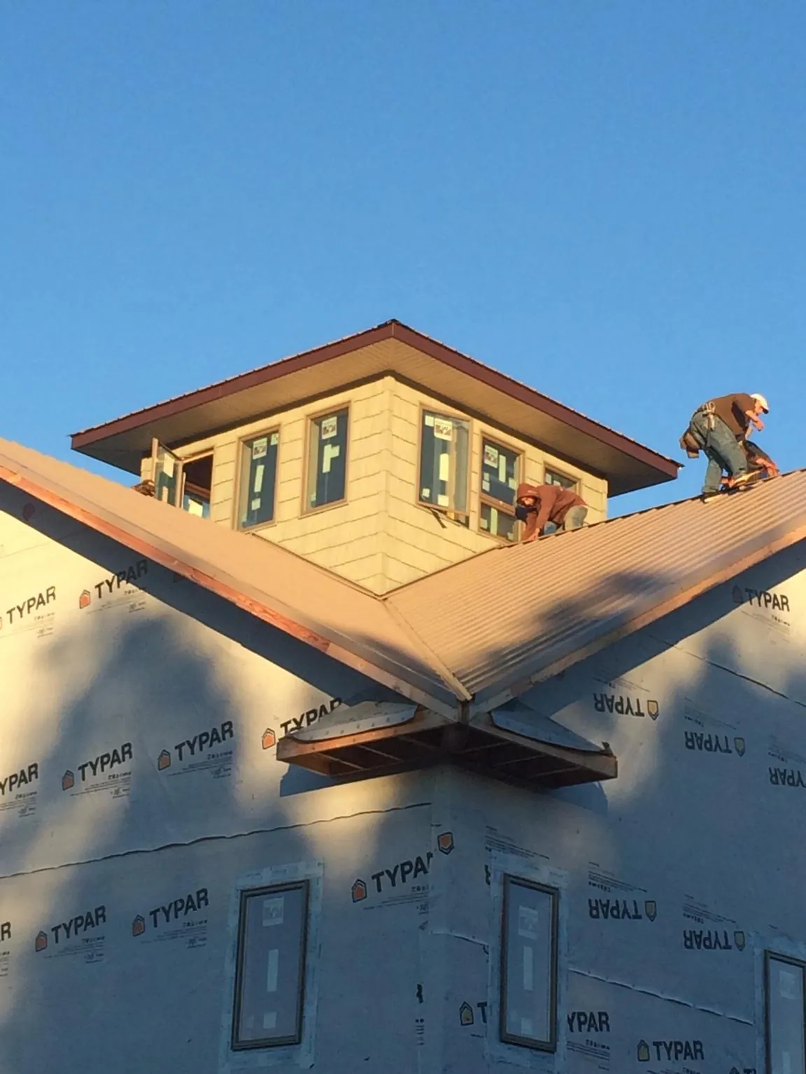 Roofers working around a rooftop cupola on a new metal roof at sunset — Roof Waterproofing in Benton City by Roofing Brothers